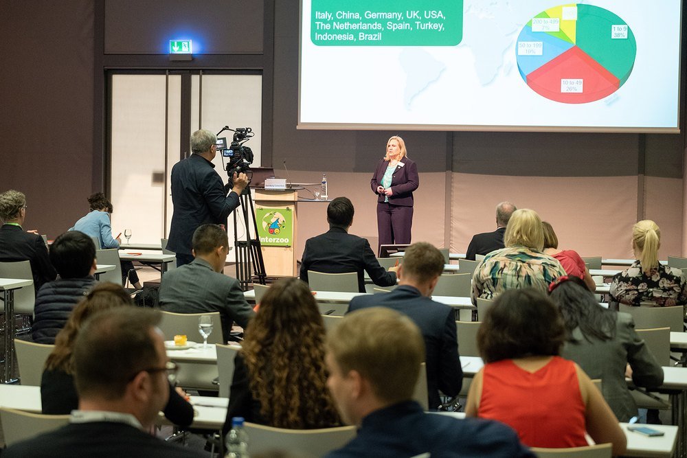 Audience at an Interzoo Academy session while a speaker presents pet market data